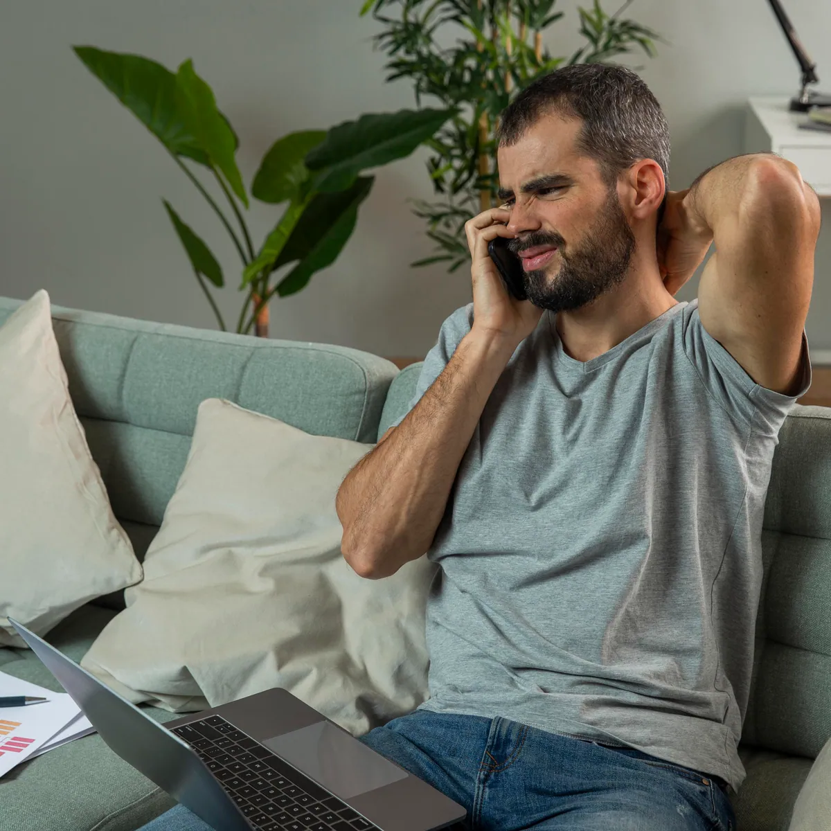Man experiencing neck pain while working laptop from home