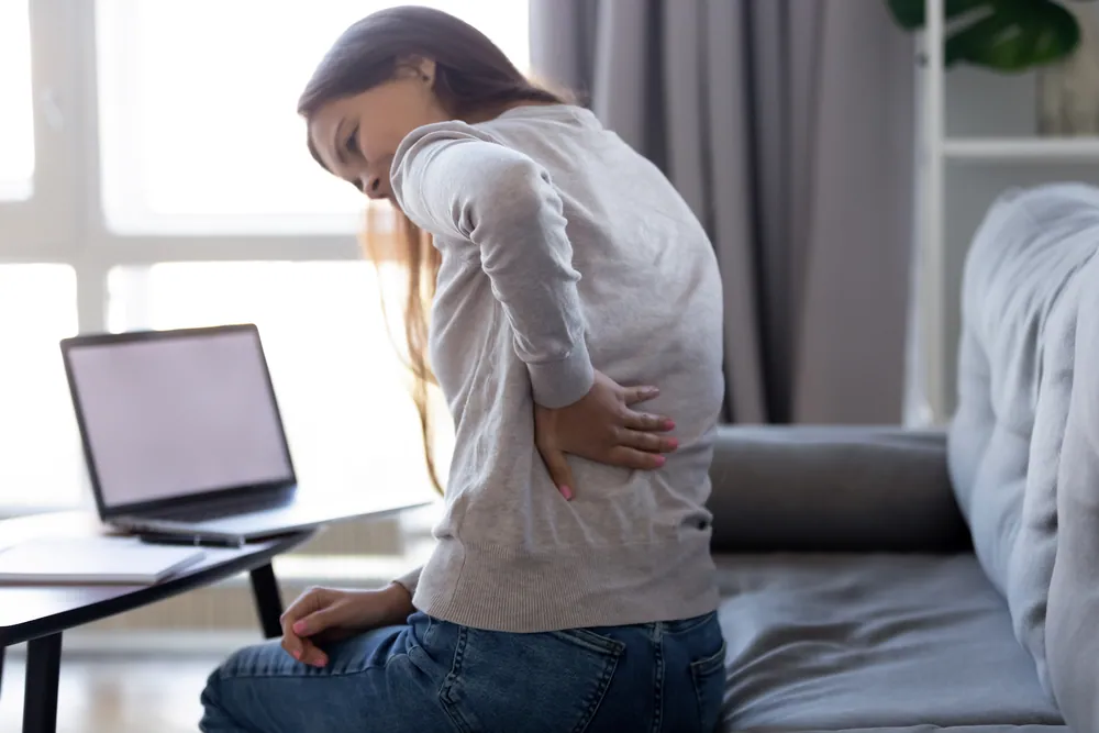 Woman experiencing back discomfort that can benefit from chiropractic wellness care