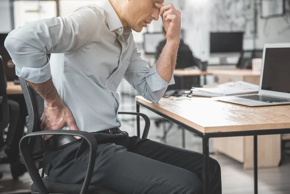 Professional experiencing acute back pain while working at a desk