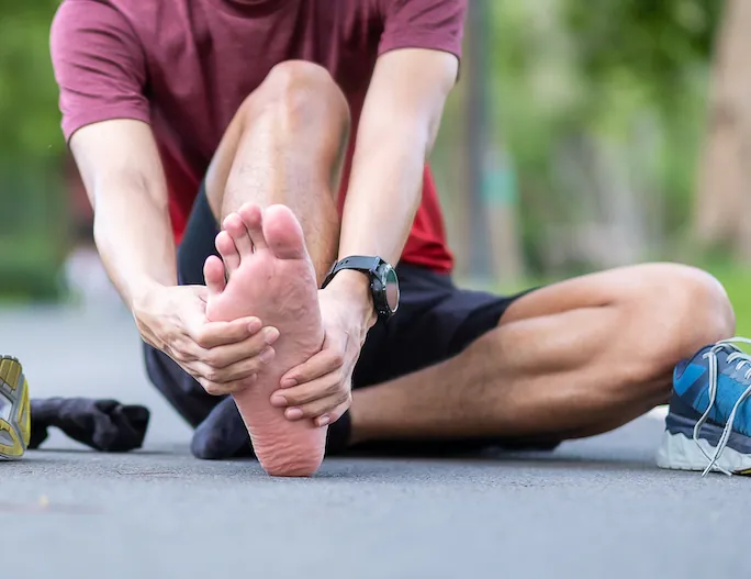 Athlete experiencing plantar fasciitis pain in the heel and arch after physical activity