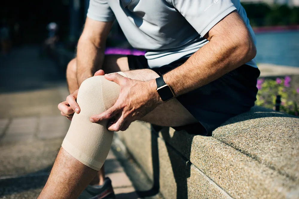 Individual with a wrapped knee recovering through chiropractic treatment