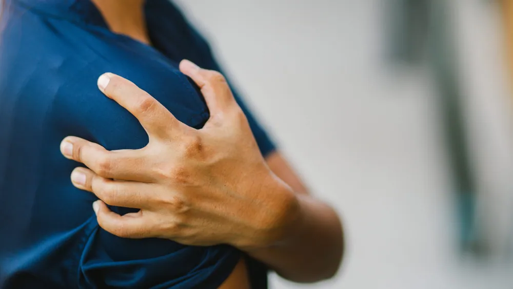 Close-up of a person gripping a painful shoulder due to a rotator cuff injury treated with chiropractic care