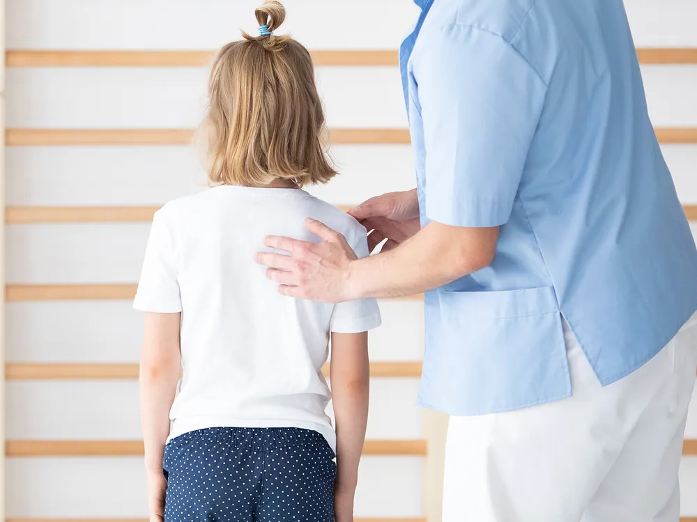 Child undergoing a chiropractic scoliosis posture screening to detect spinal curvature early