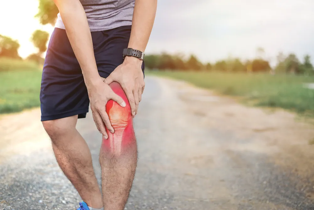 Close-up of a person supporting an injured knee with ligament strain before chiropractic treatment for sprains and strains